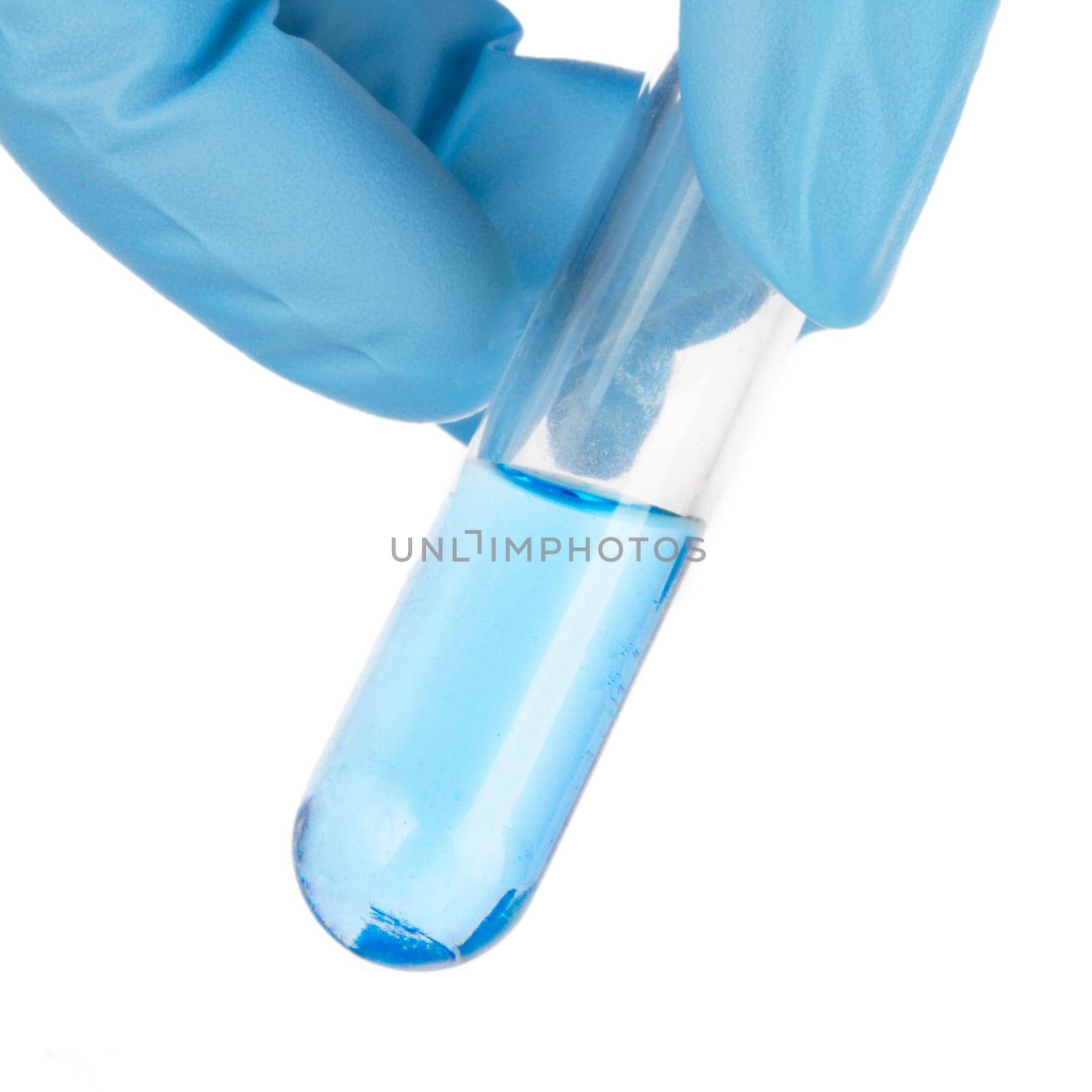 Fingers holding test tube with blue liquid.