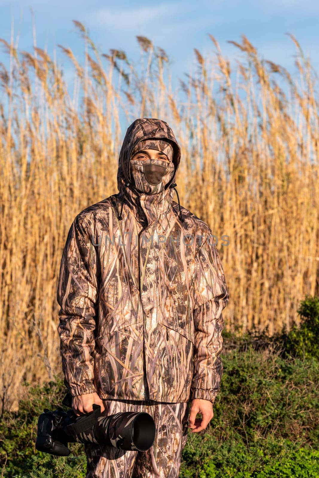 Naturalist photographer in action, with camouflage and camera, in the wilderness.