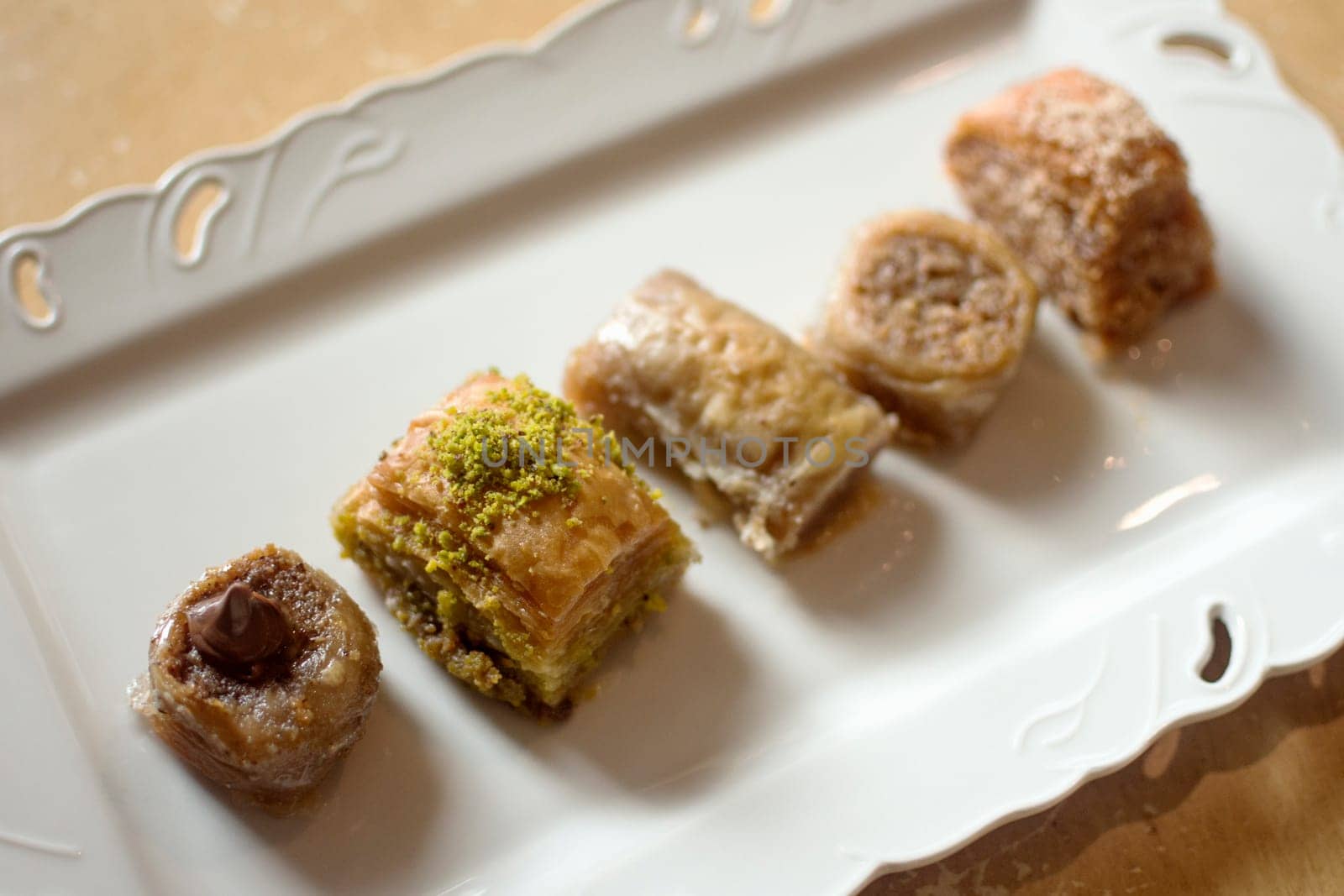 Five different mini baklava traditional turkish dessert on white plate.