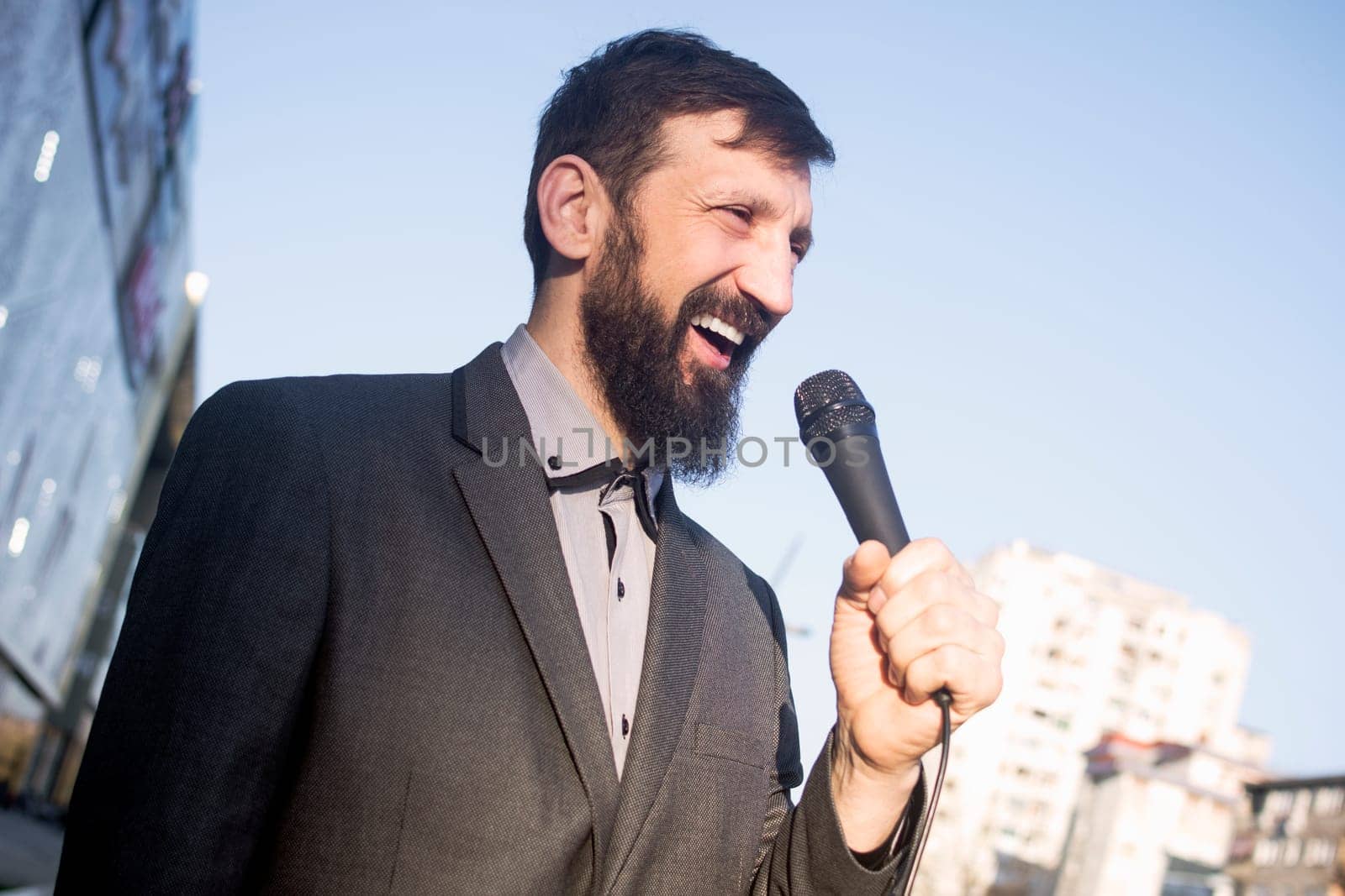 The smiling TV reporter is talking in microphone at the street.