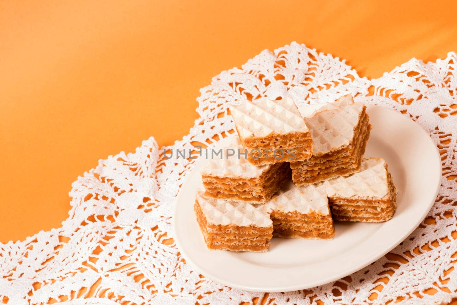 Filled wafer cake sweet dessert is on plate on orange background.
