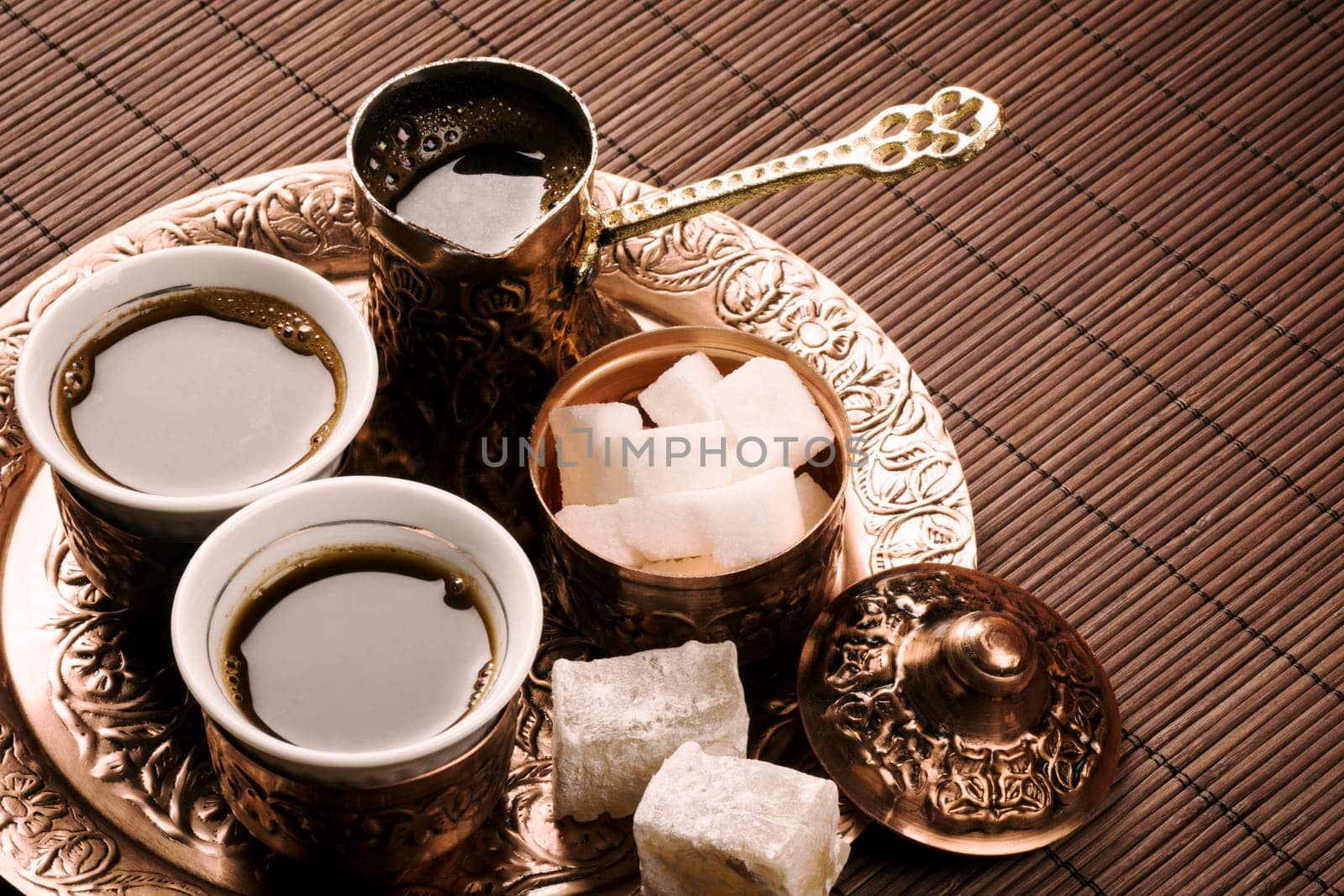 Traditional Turkish coffee set with two coffee cups, sugar and Turkish delight on brown background.