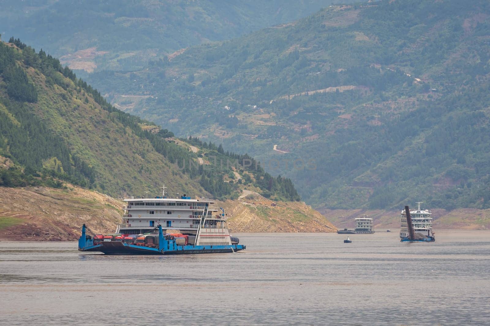 Yangtze River, China - August 2019 : Cargo ship ship transporting trucks and other vehicles sailing through the gorge on the magnificent Yangtze River