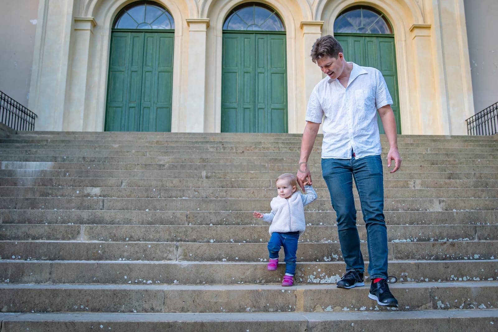 father and daughter go down the stairs and hold hands