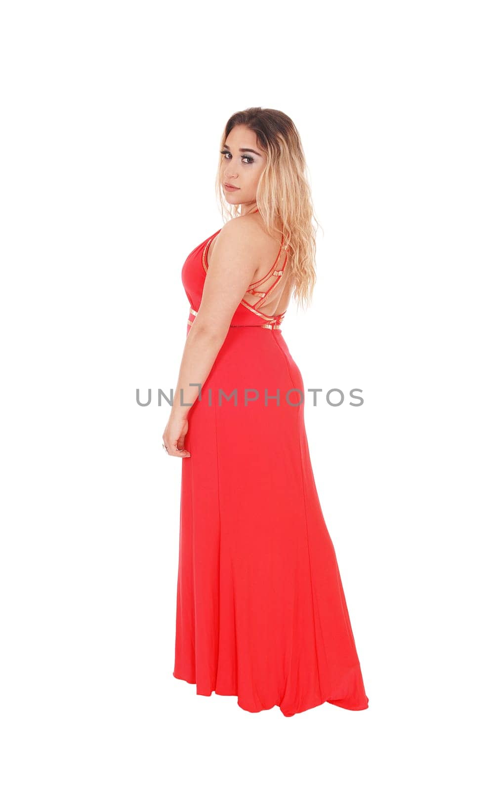 Lovely young woman standing in a long red evening dress in profile.looking into the camera, isolated for white background.