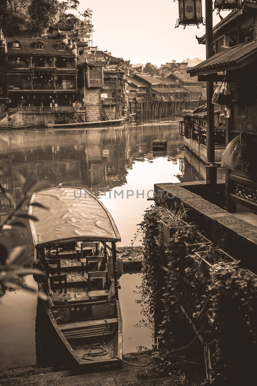 Old historic wooden tourist boat on the riverbanks of Tuo river, flowing through the centre of Fenghuang Old Town, China