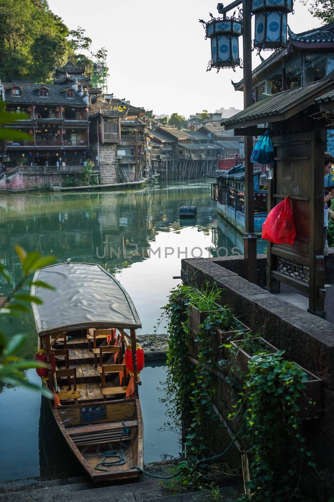Old historic wooden tourist boat on the riverbanks of Tuo river, flowing through the centre of Fenghuang Old Town, China