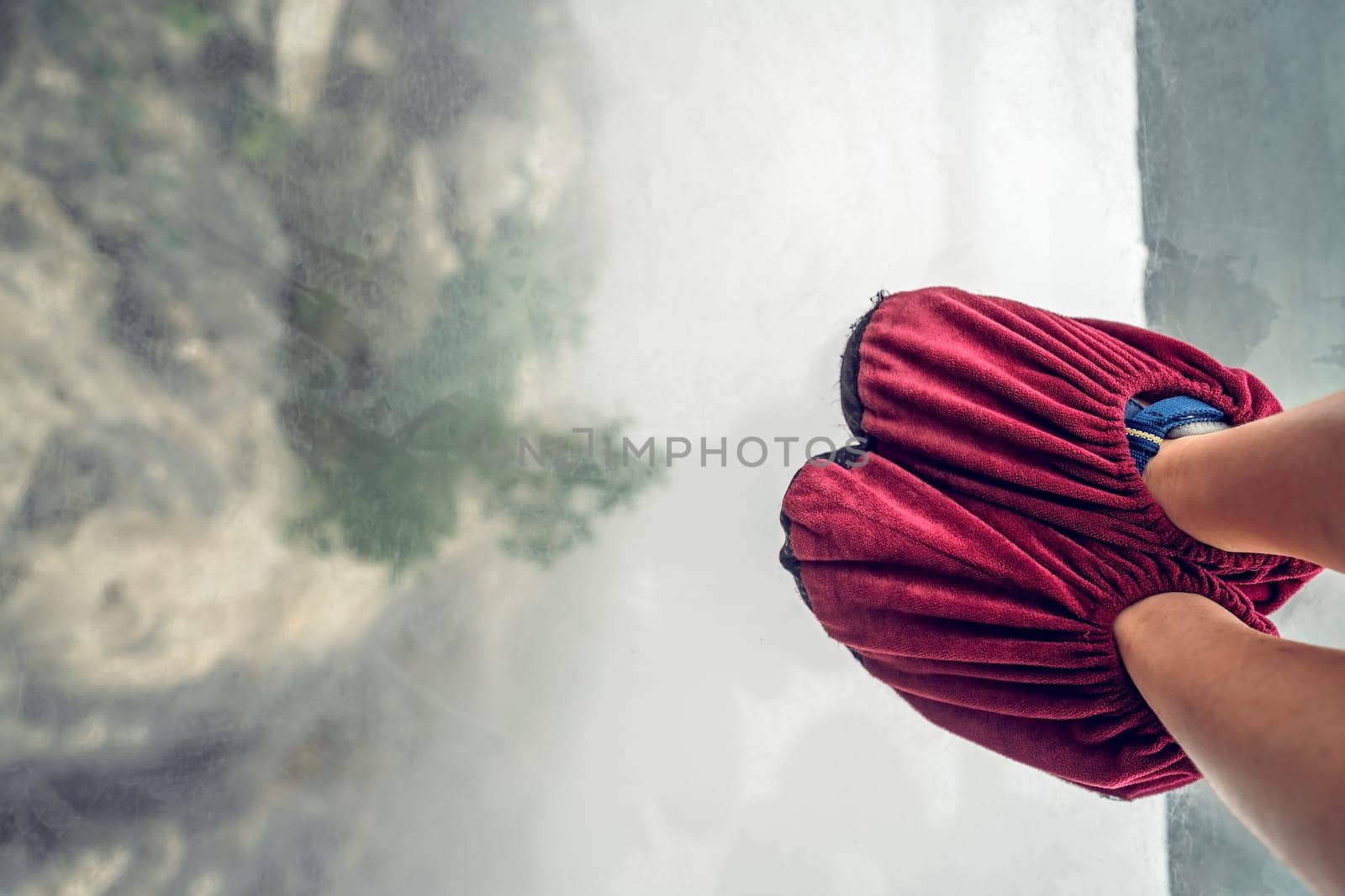 Little tourist girl wearing in shoe covers while standing on glass pathway in Tianmenshan nature park, Zhangjiajie, China