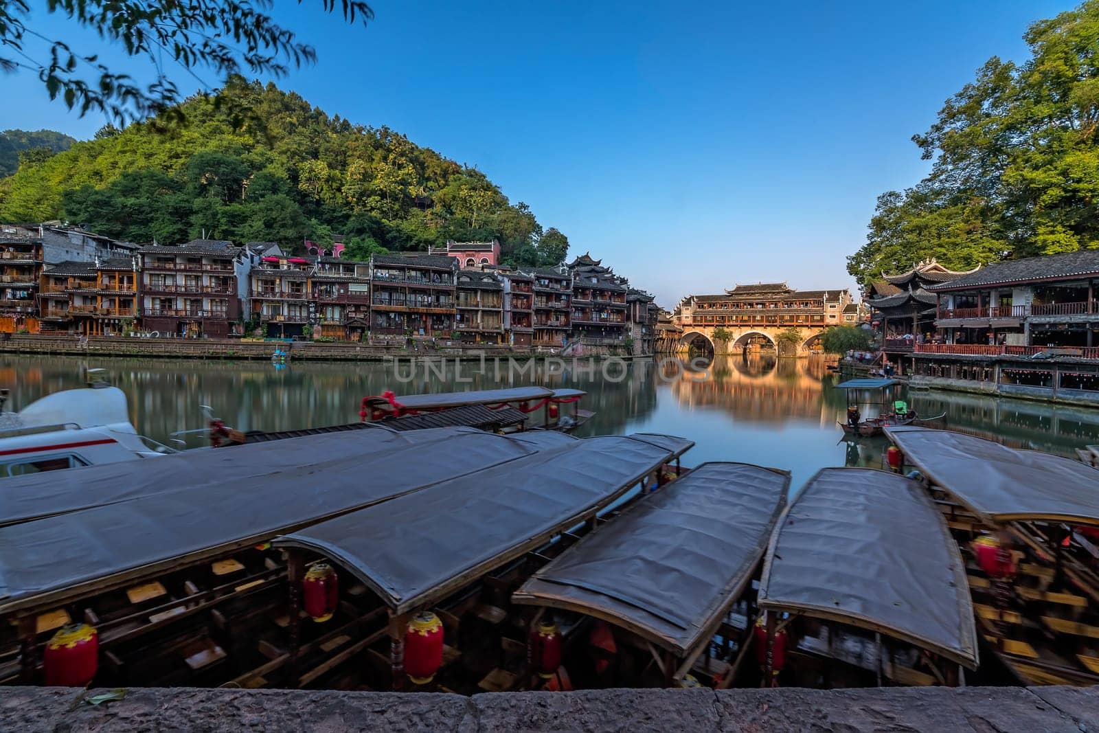Old historic wooden tourist boats on the riverbanks of Tuo river, flowing through the centre of Feng huang Old Town, China