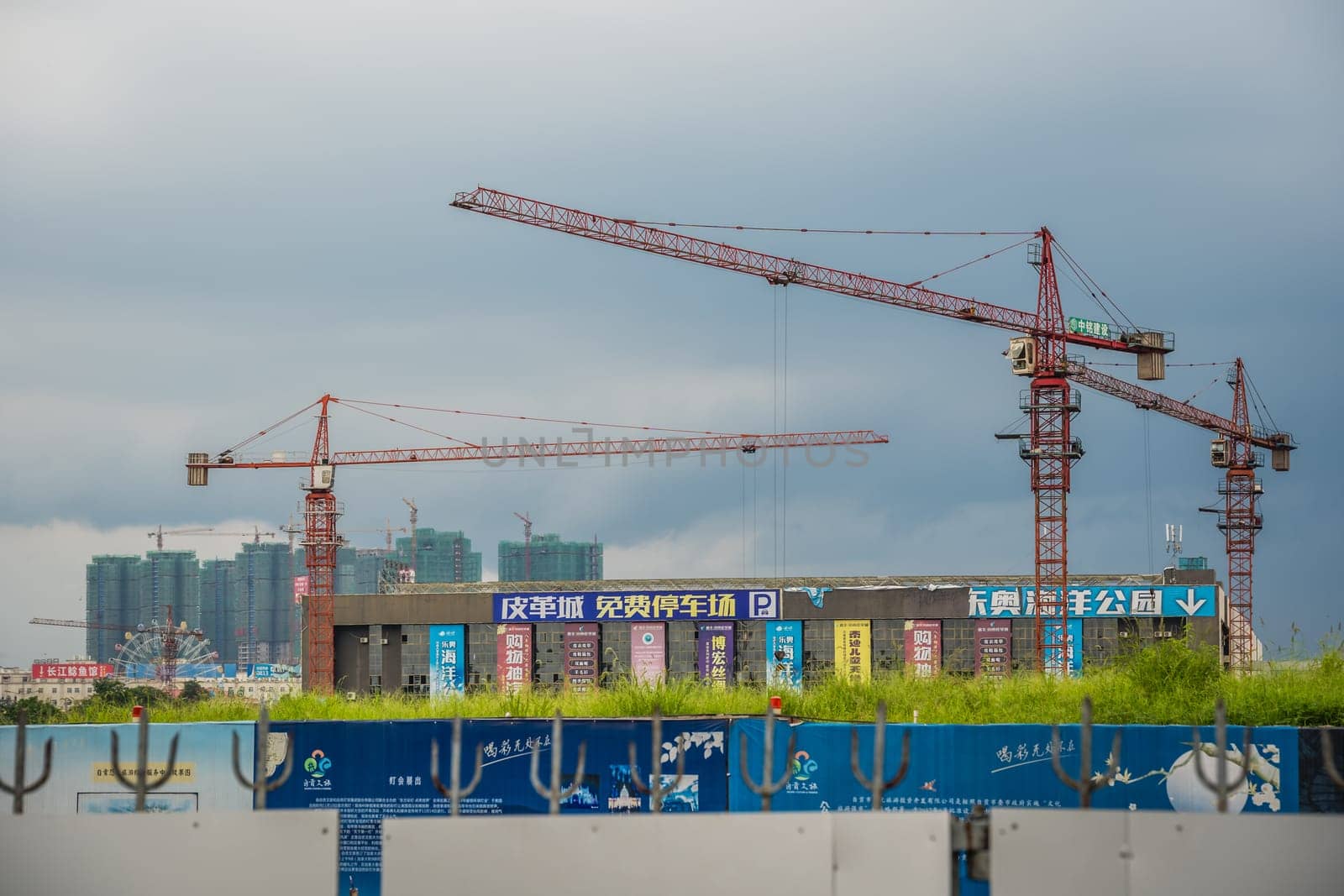 Zigong, China -  July 2019 : Tall cranes on a working construction building site, Sichuan Province