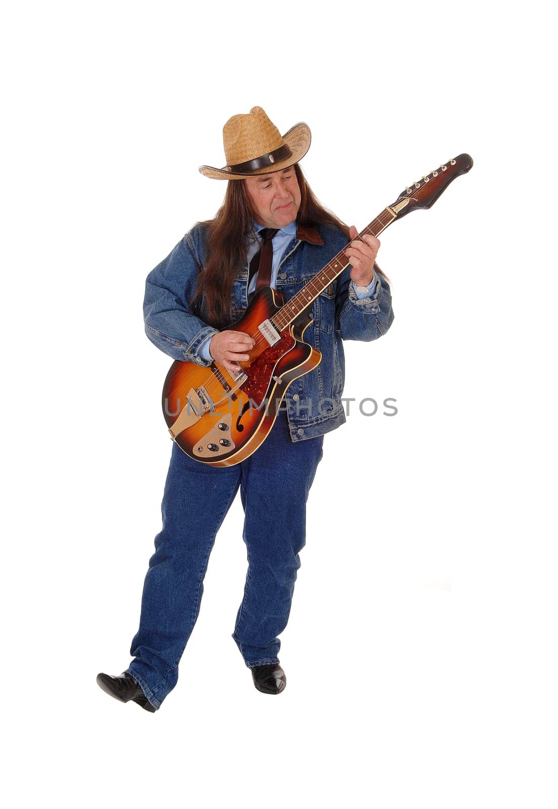 A handsome indigenous man in a jeans jacket, pants and a cowboy hat.standing and playing the guitar, isolated for white background.