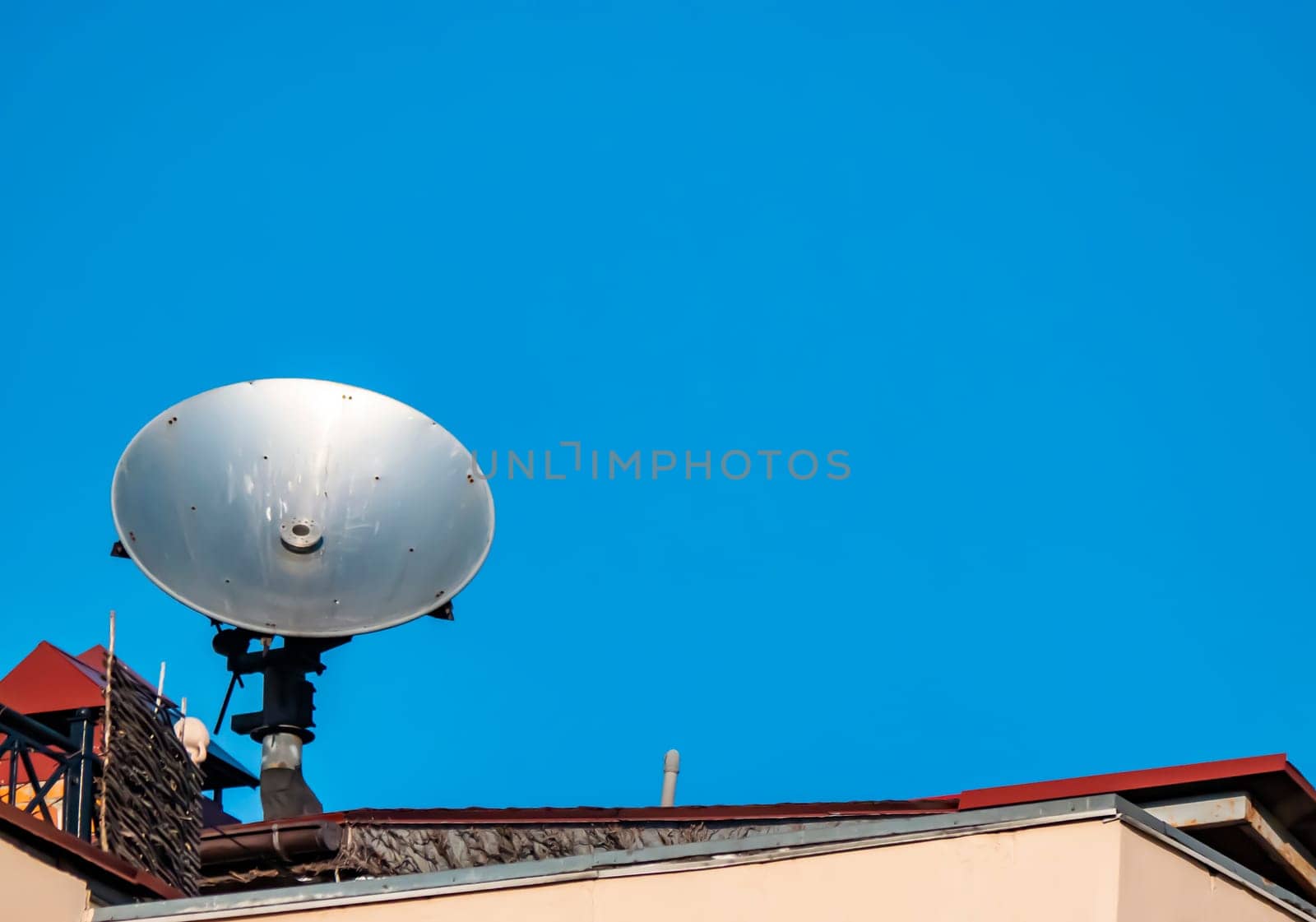 Satellite dish on the roof of the building against the blue sky. Technology. Place for text. Background image.