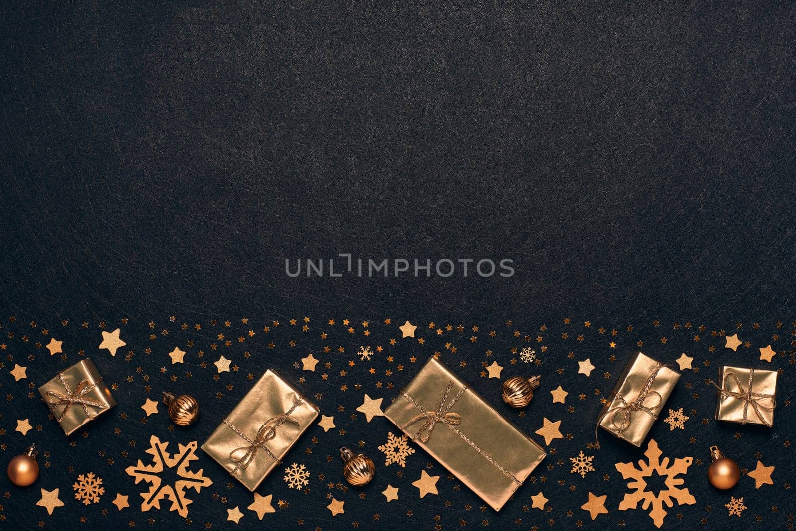 Festive composition with golden Christmas decorations and gold gift boxes on black textured background. Top view with copy space, Design element for greeting card, invitation, advertising, winter sale