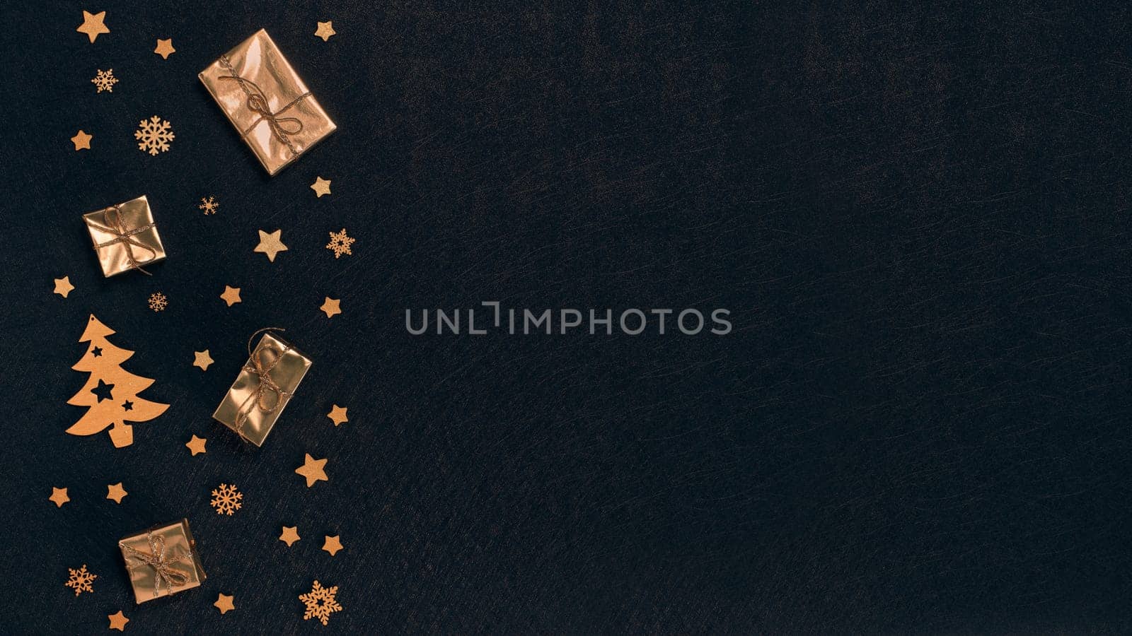 Festive composition with golden Christmas decorations and gold gift boxes on black textured background. Top view with copy space, Design element for greeting card, invitation, advertising, winter sale