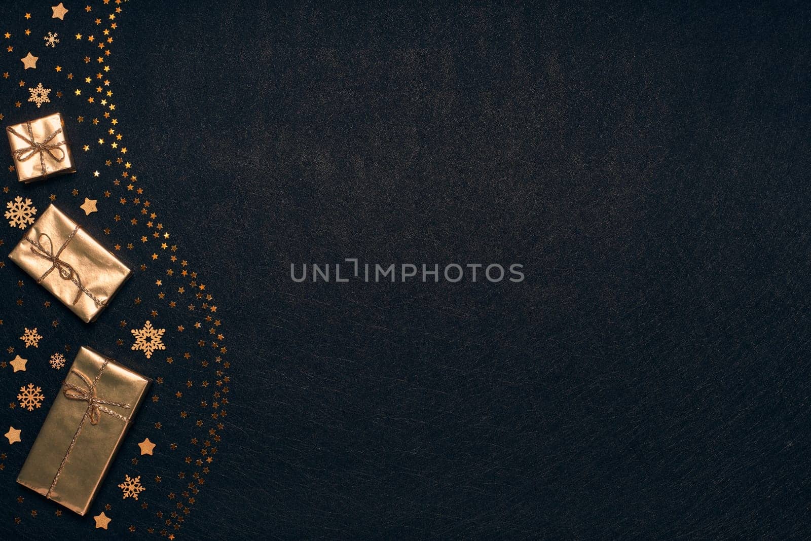 Festive composition with golden Christmas decorations and gold gift boxes on black textured background. Top view with copy space, Design element for greeting card, invitation, advertising, winter sale