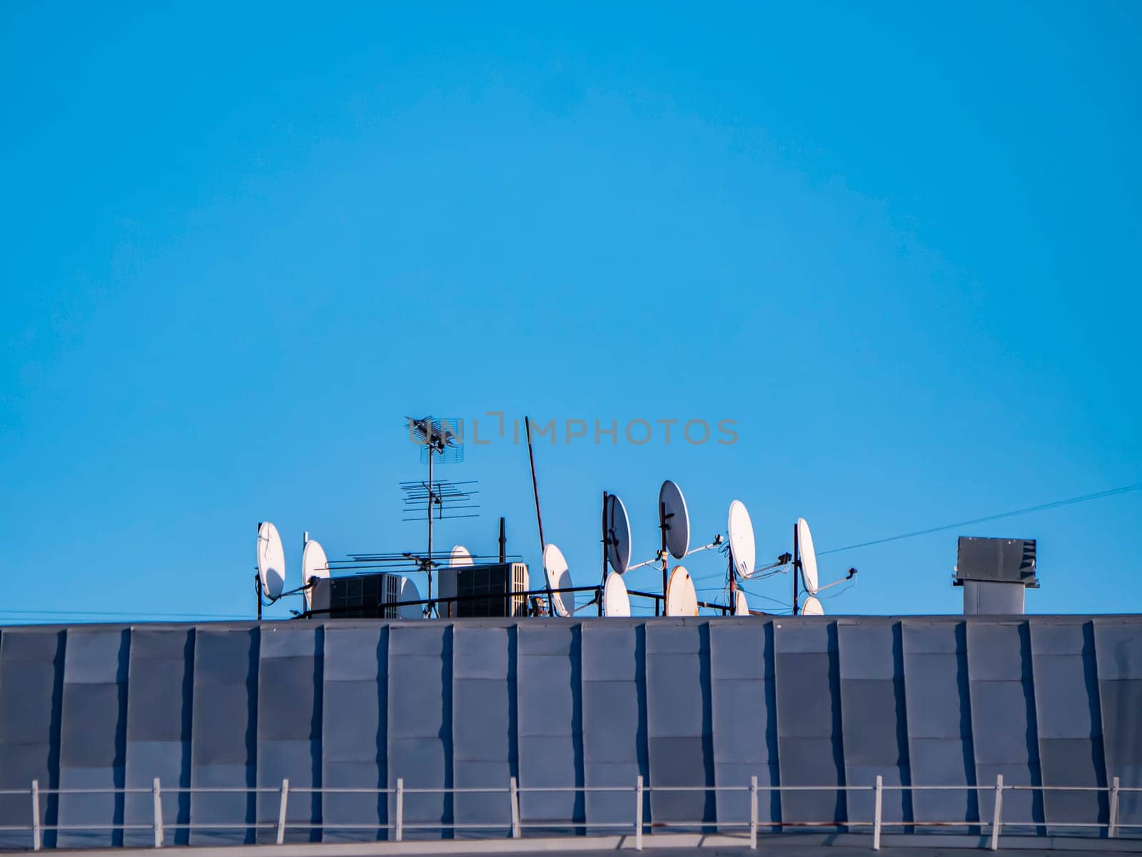 Satellite dishes on the roof of a building with place for text. Technology. Blue sky. Communication.
