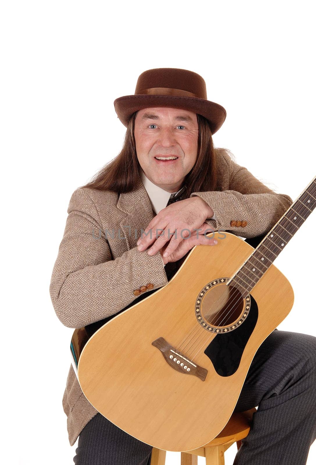 A middle age man sitting in a brown jacket and hat.and holding his beloved guitar, isolated for white background.