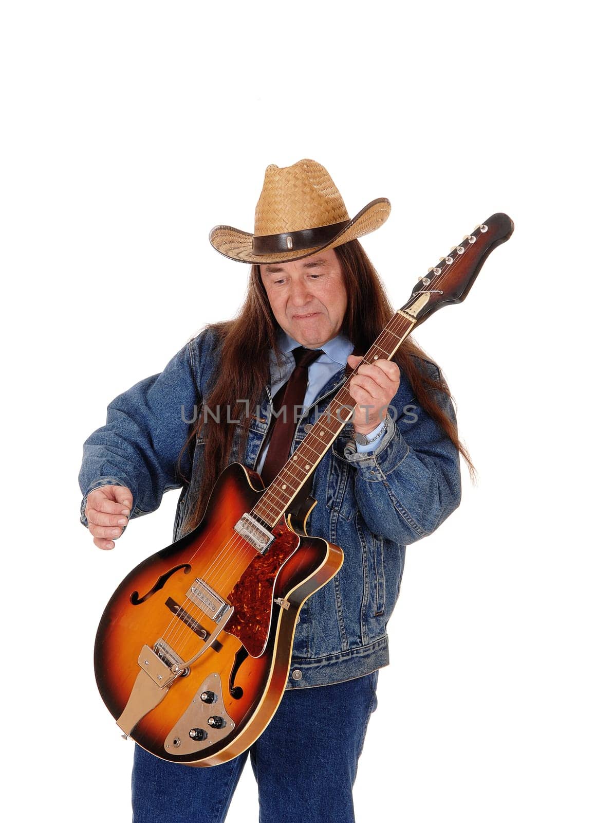 A handsome indigenous man in a jeans jacket, pants and a cowboy hat.standing and playing the guitar, isolated for white background.