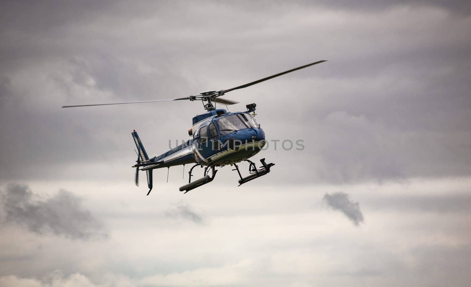 Blue helicopter in flight over a gray sky