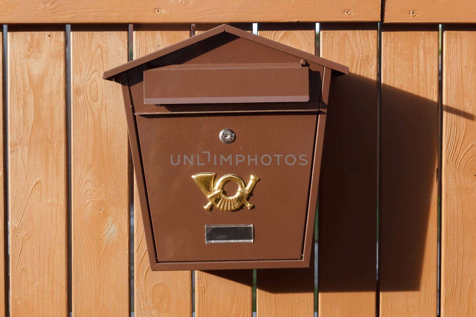 Brown metalic mailbox on brown wood Fence