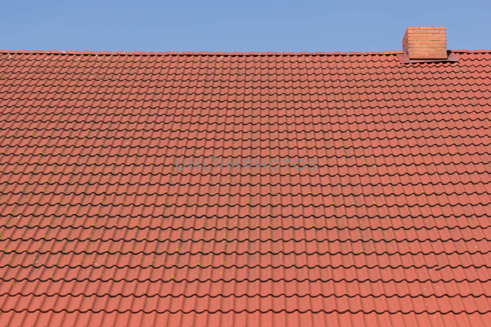 red tile roof with chimney against blue sky