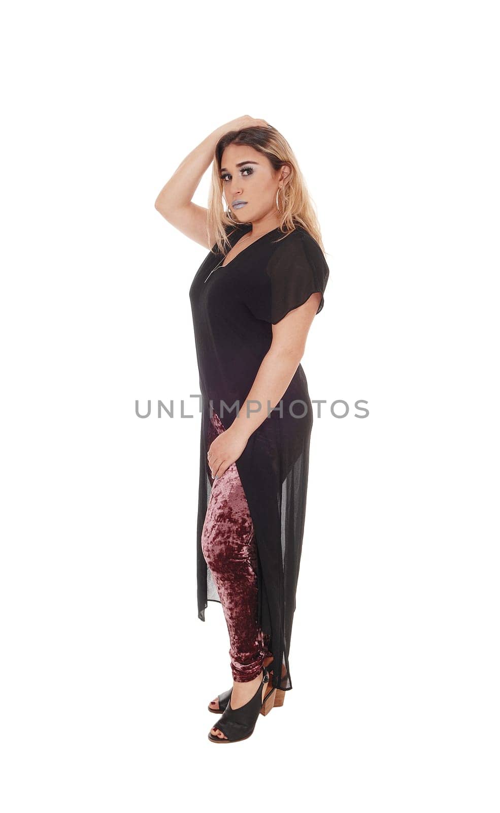 A lovely young woman standing in profile in black dress and .colorful tights under, isolated for white background.