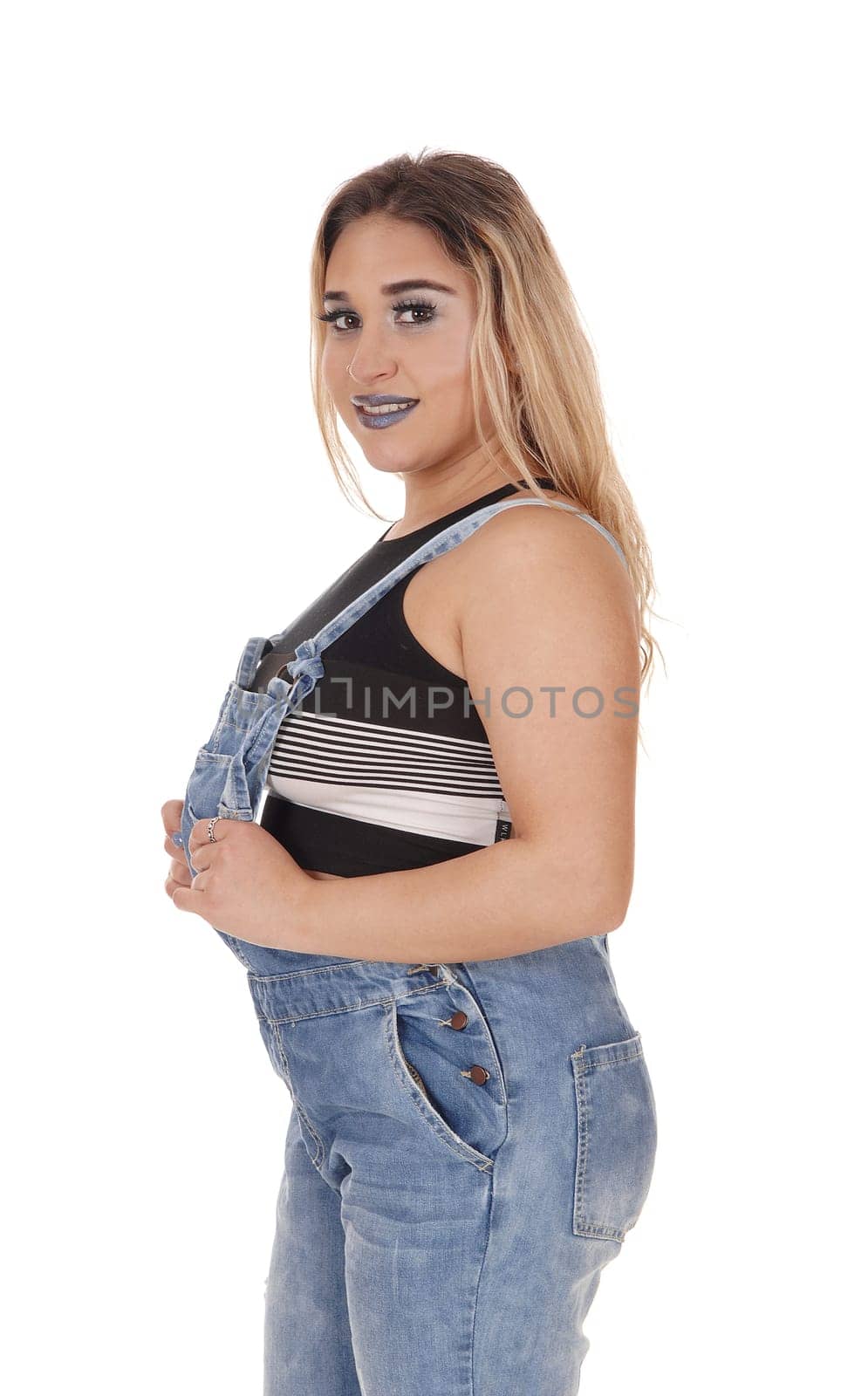 Beautiful young woman standing in a working jeans .in profile, looking into the camera, isolated for white background.