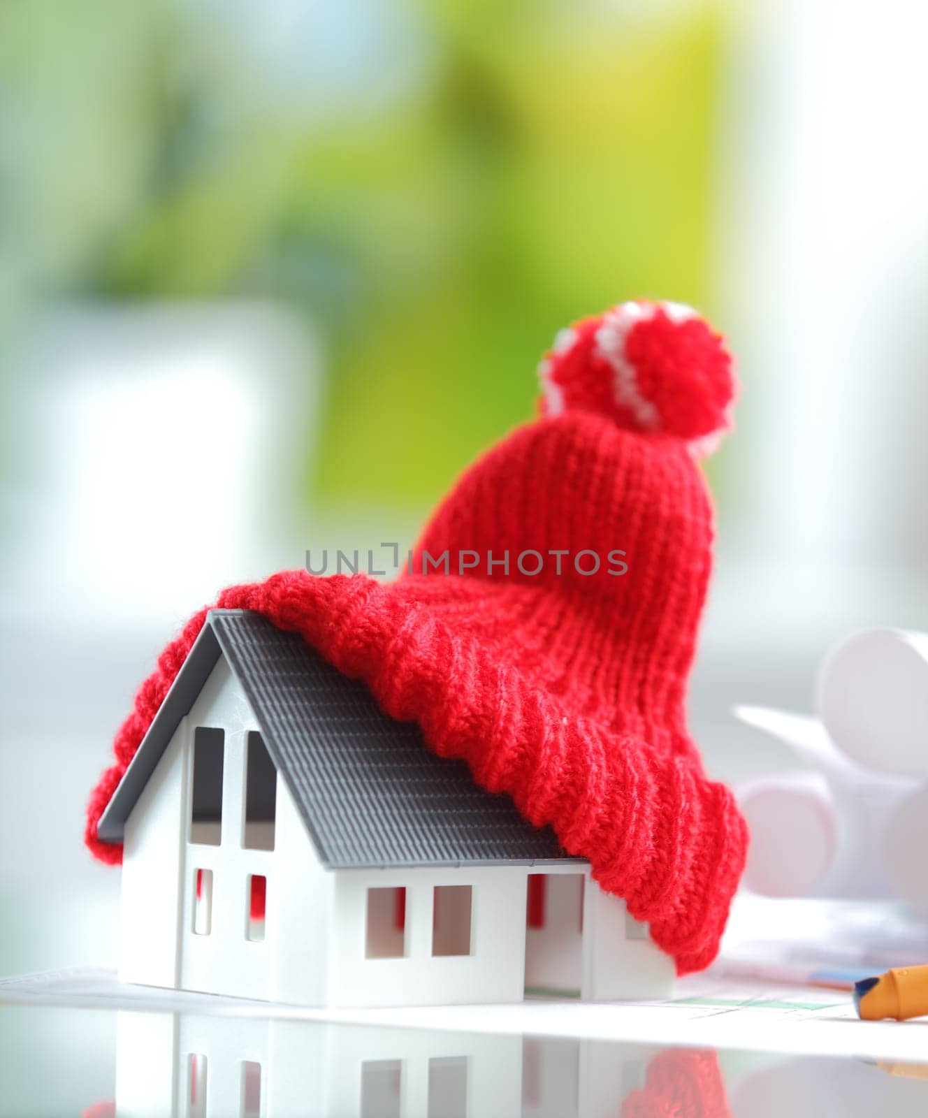Energy saving Shot of Conceptual Red Knitted Hat on Top of Miniature House for isolation and insulation concepts