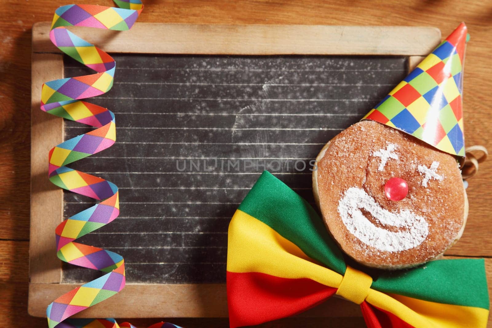 Close up Decorated Carnival Donuts with Hat, Ribbon and Confetti, In Front Black Board. Emphasizing Copy Space for Texts.