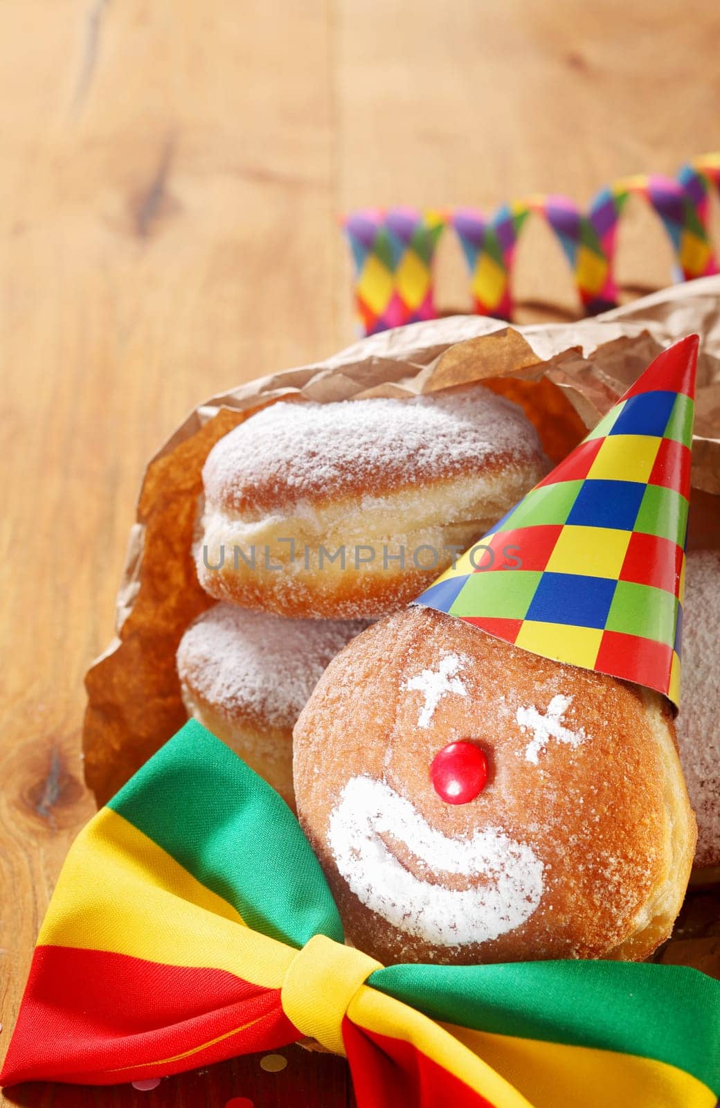 Close up Carnival Donuts with Clown Face Decorated with Colored Hat and Ribbon on Wooden Table.