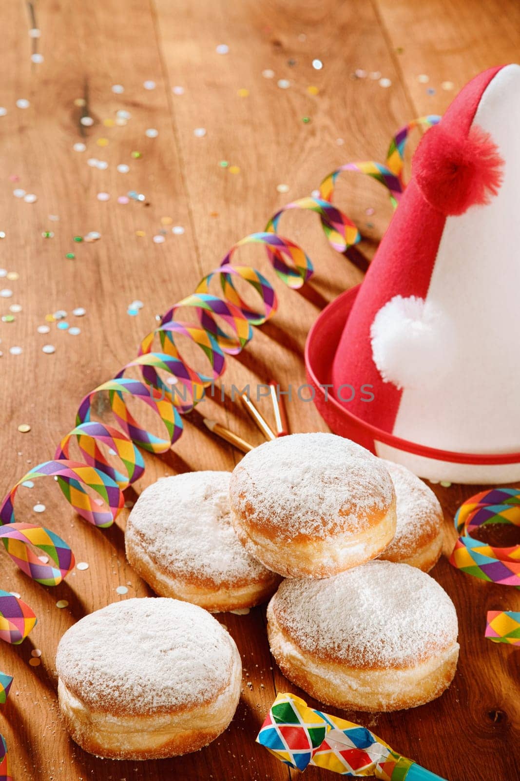 Close up Delicious Powdered Sugar Donuts with Carnival Props on Side on Top of Wooden Table.