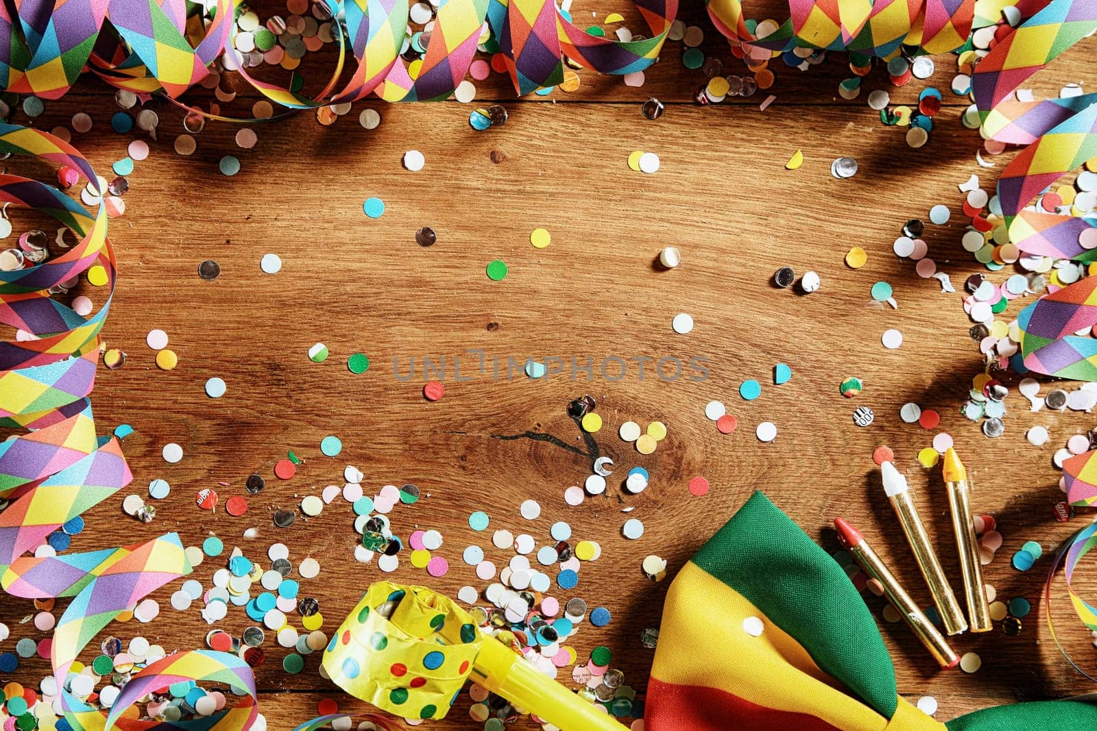 Close up Wooden Table with Festival Props - Confetti, Paper Streamers, Whistle, Ribbon and Pencil. Emphasizing Copy Space.
