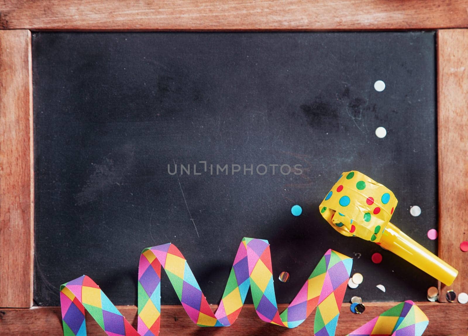 Close up Colored Festival Paper Streamer, Confetti and Whistle on Black Board. Emphasizing Copy Space.