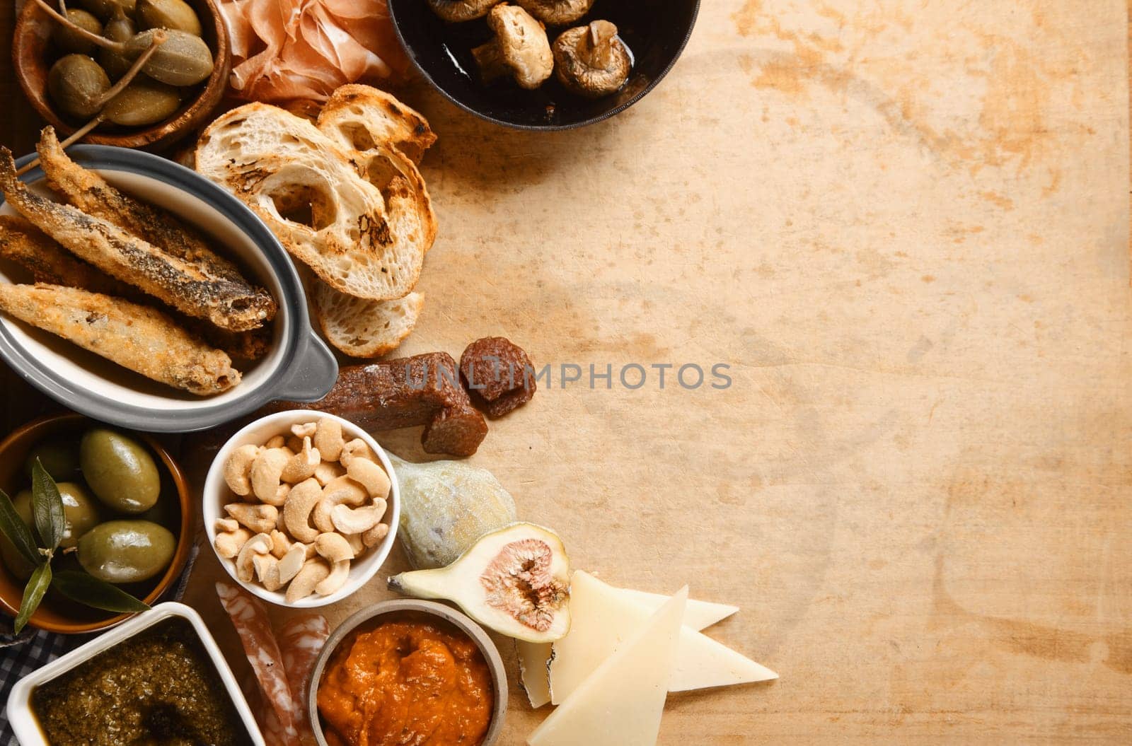 Close up Tasty Tapas on Wooden Table with Copy Space on Right. Emphasizing Batter Fried Fish, Olives, Nuts and Breads.