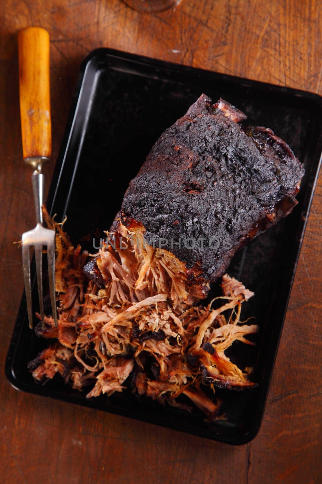 Aerial Shot of Tasty Pulled Pork Dish on Black Tray with Fork. Placed on Wooden Table.