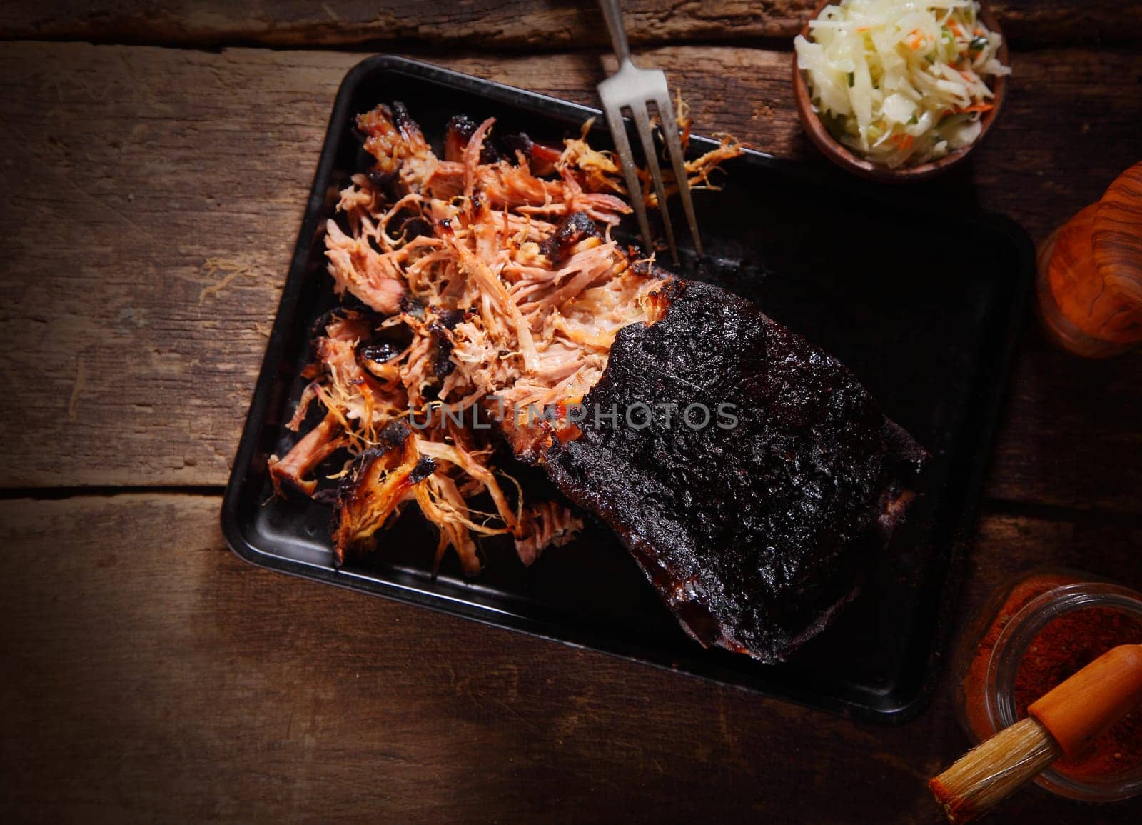 Aerial Shot of Mouth Watering Pulled Pork Dish on Black Serving Tray with Fork. Served on Wooden Table.