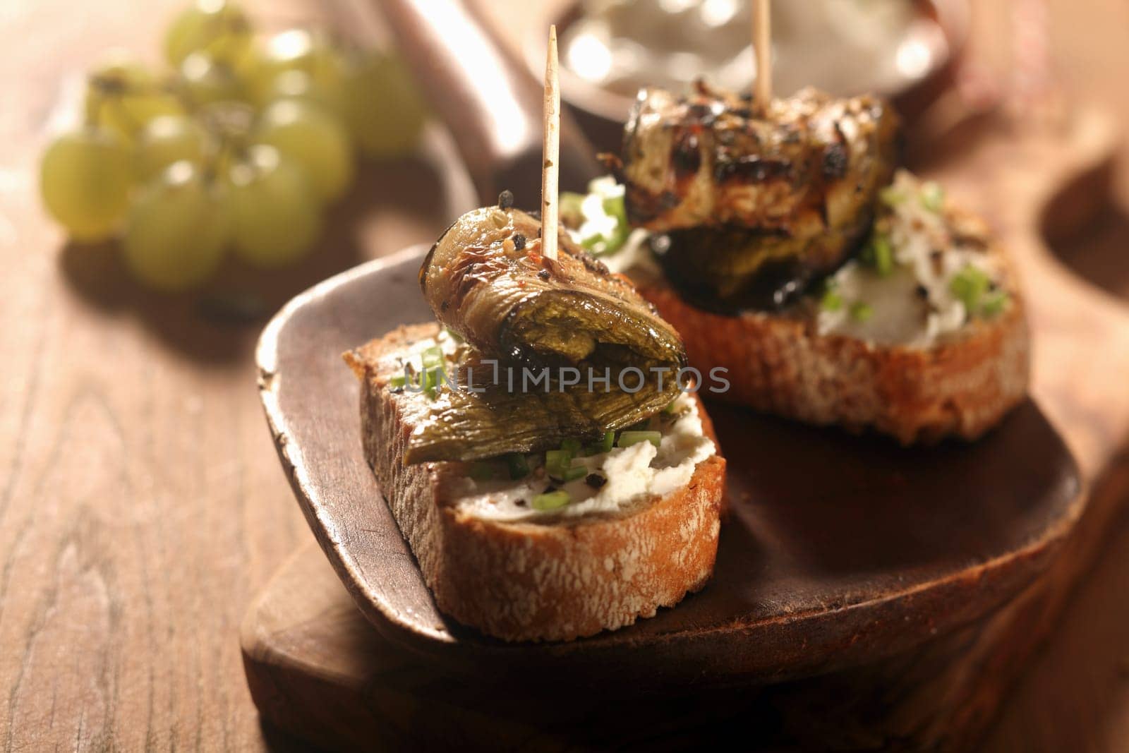 Close up Gourmet Toasted Bread with Appetizing Roasted Rolled Fish Meat on Wooden Serving Ladle on Wooden Table.