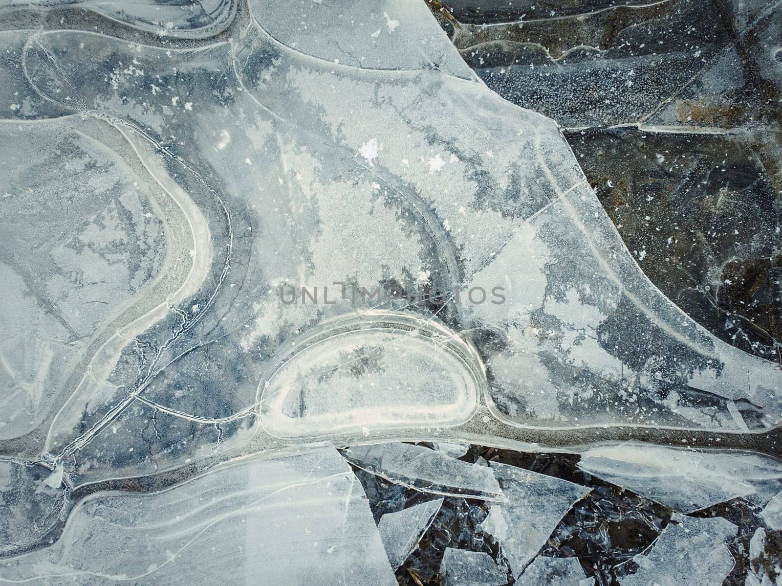 Close up abstract background of a frozen puddle. Cracked pothole ice texture, winter season pattern.