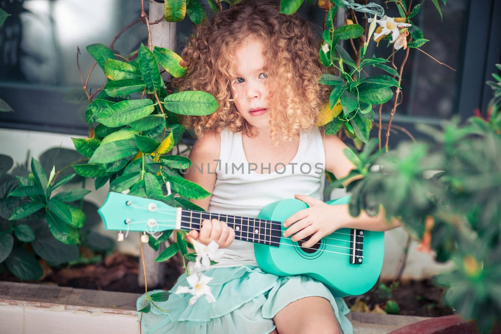 Portrait of a cute girl sitting ouddoor with ukulele