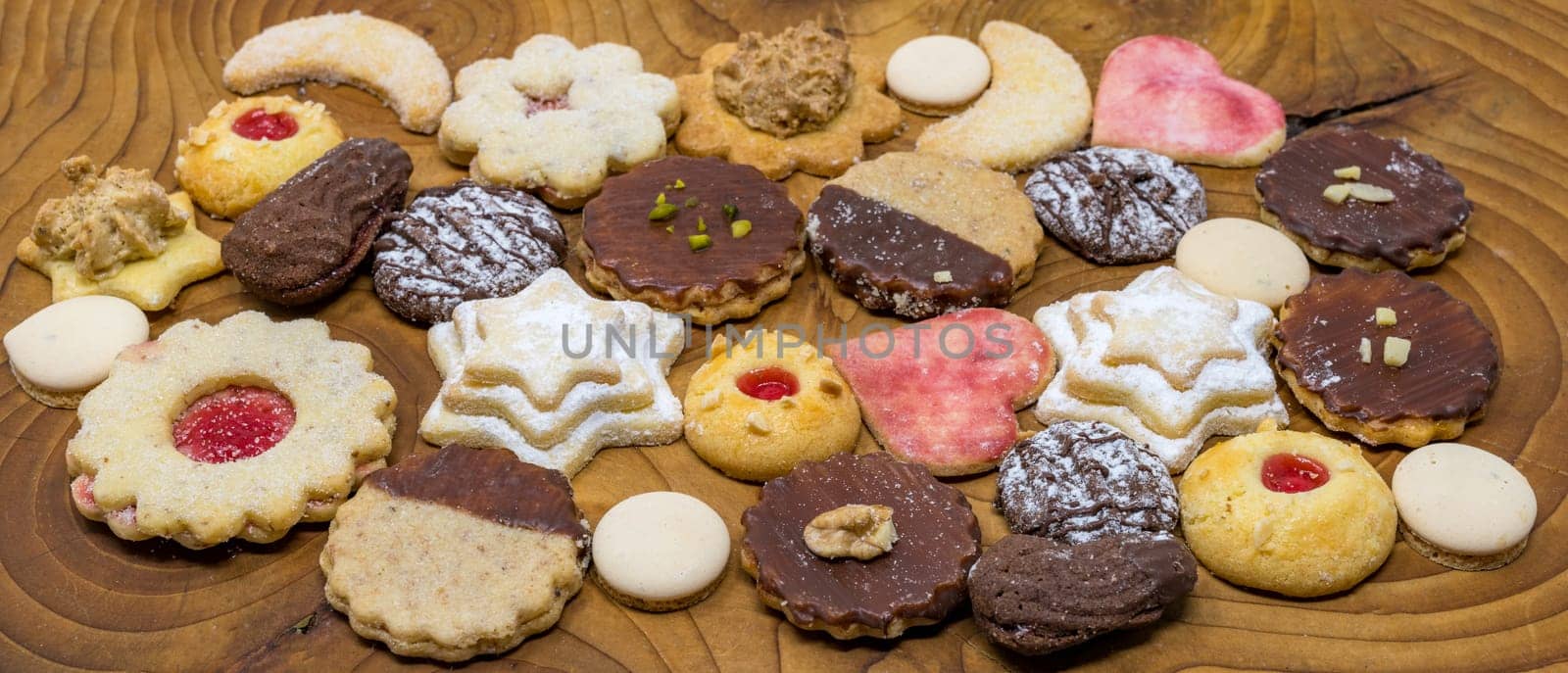 colorful mix of homemade christmas cookies on a dark wooden board
