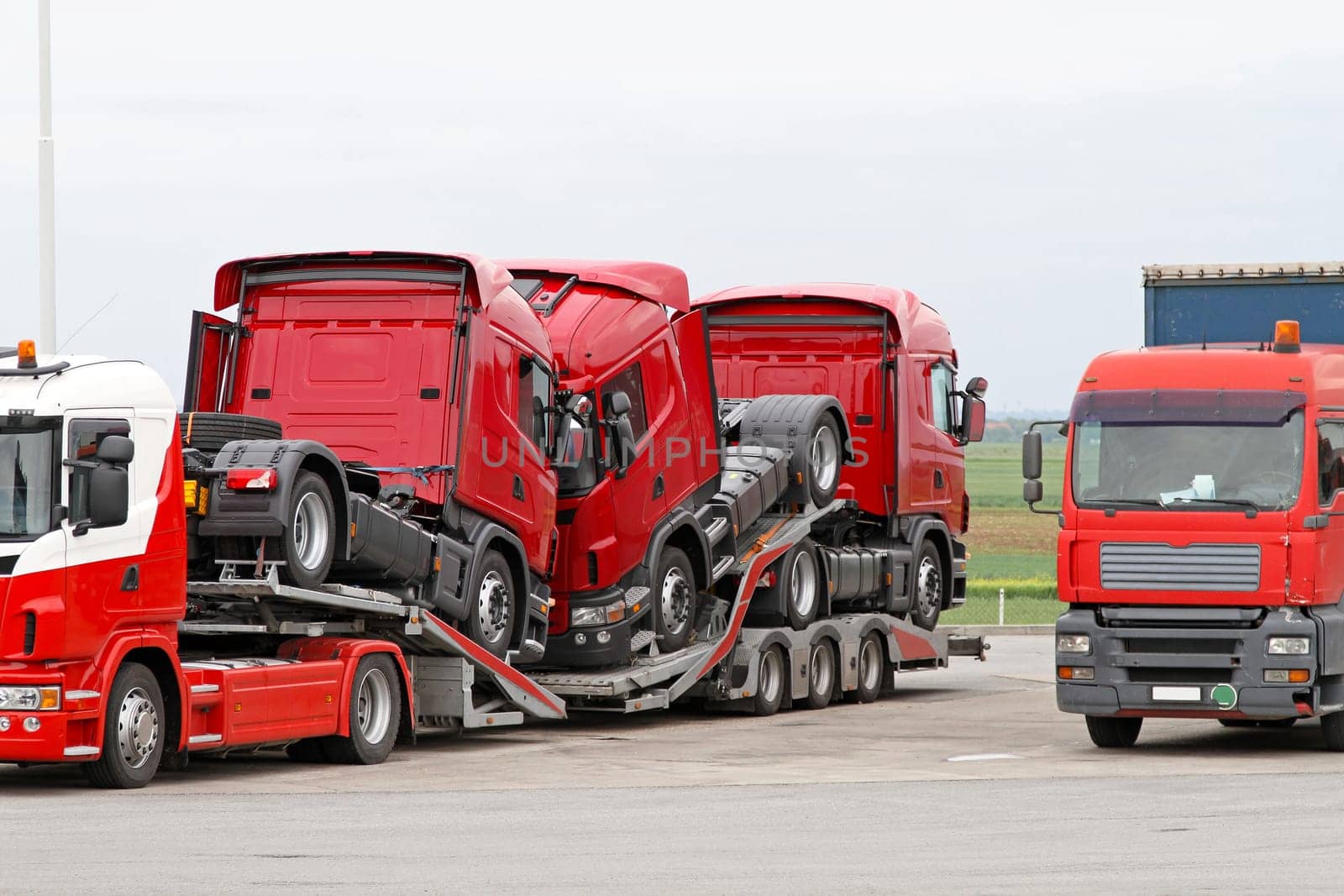 Transporting new red semi trucks at lorry
