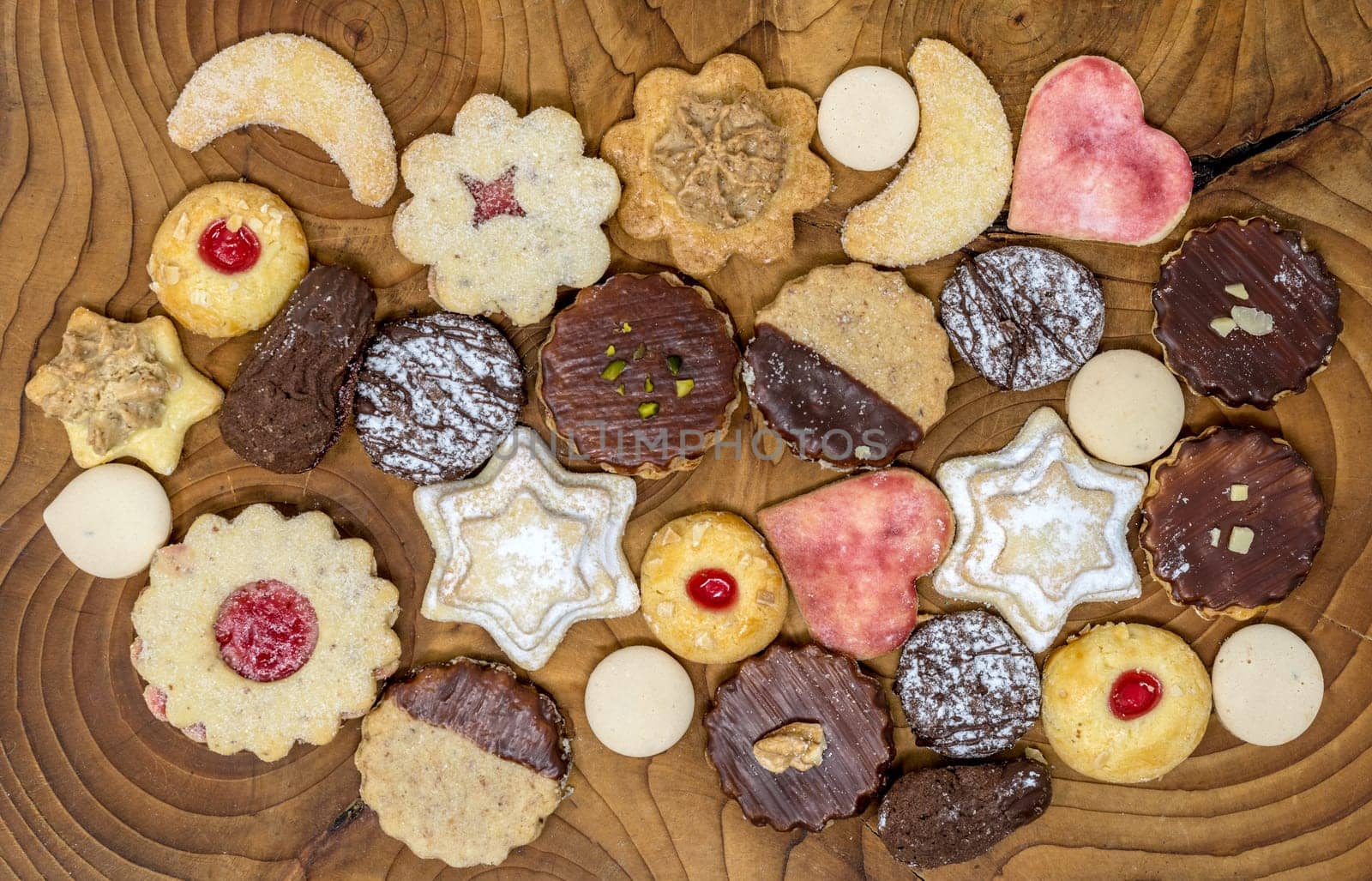 colorful mix of homemade christmas cookies on a dark wooden board
