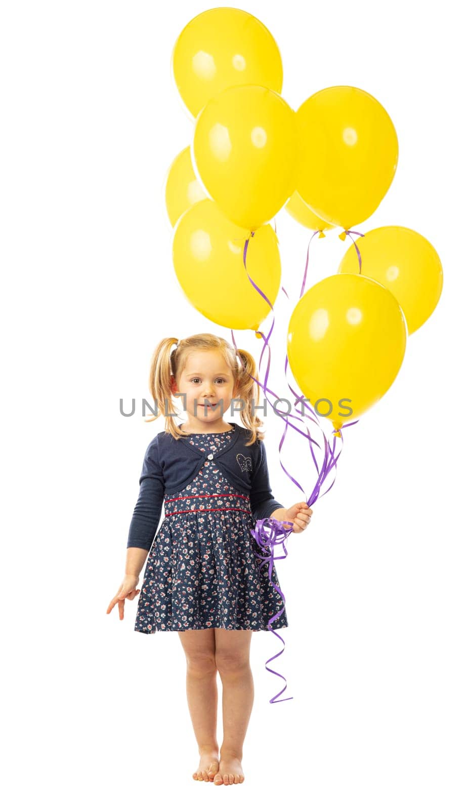 portrait of a smiling blonde 3 year old girl holding a group of yellow balloons. isolated on white