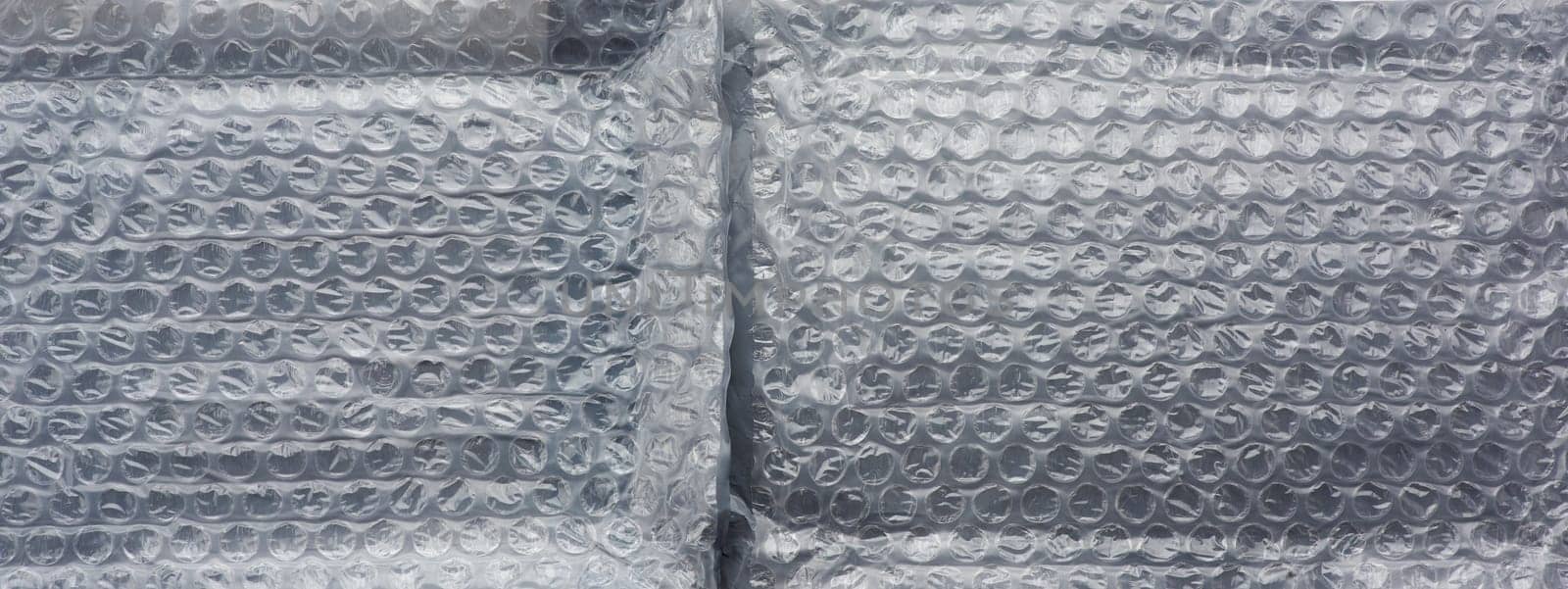 fragment of a transparent film with air for transportation of parcels is glued on gray polyethylene, inside of the envelope. White polyethylene texture.