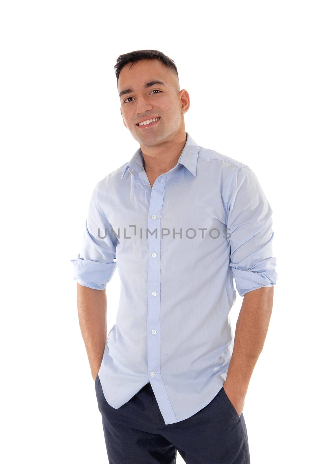 A handsome east Indian man standing in dress pants and a blue shirt.relaxed in the studio, smiling, isolated for white background.