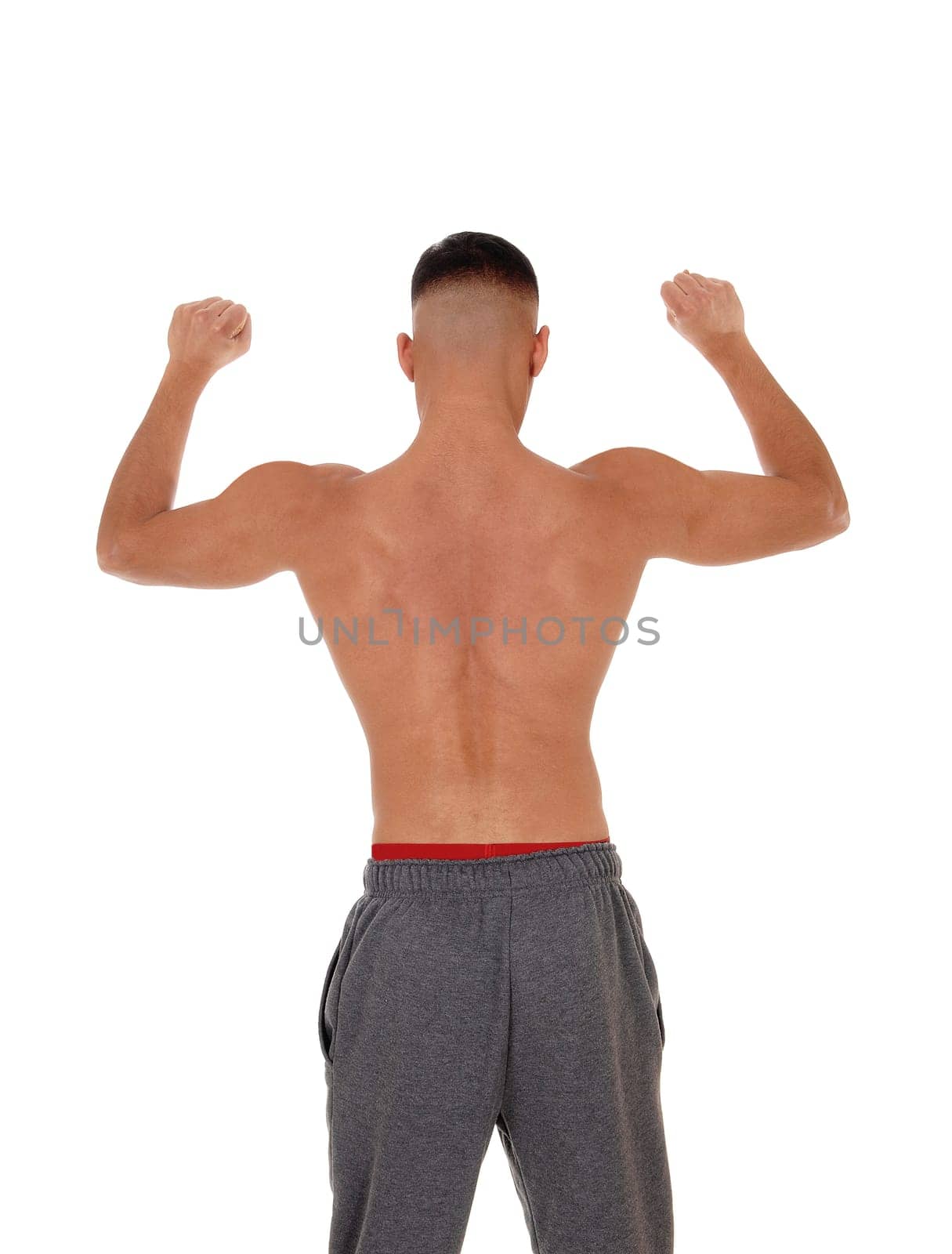 A handsome young east Indian man standing shirtless from the back.in track pants with red underwear, isolated for white background.