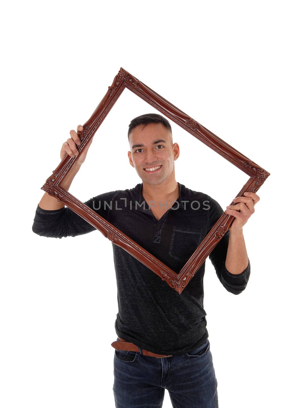 A happy east Indian man standing behind a brown picture frame in a.black dress shirt with a big smile, isolated for white background.