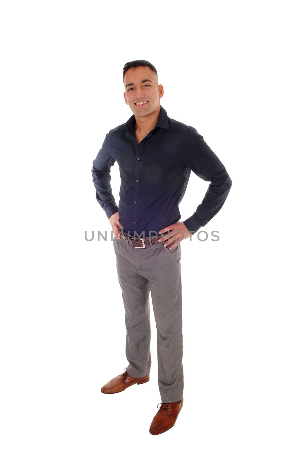 A handsome young east Indian man standing in a black shirt with his.hands on his hips, smiling, isolated for white background.