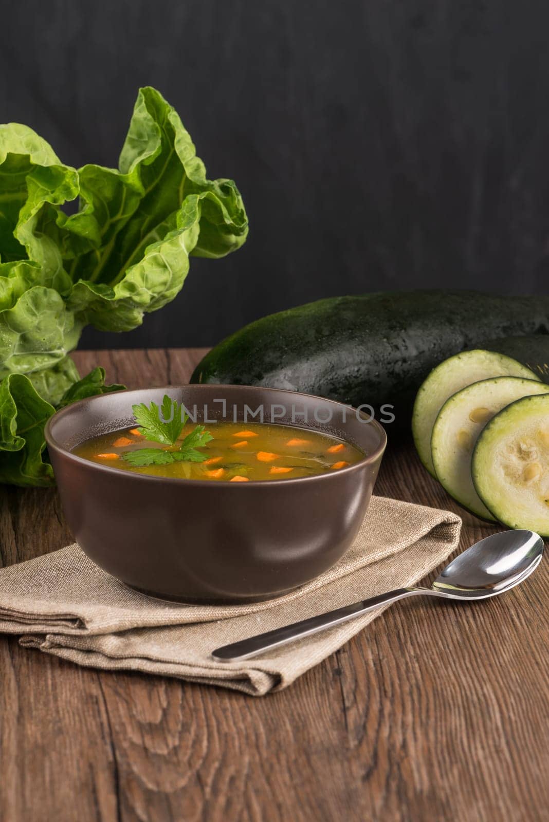Soup with vegetables on wooden table.