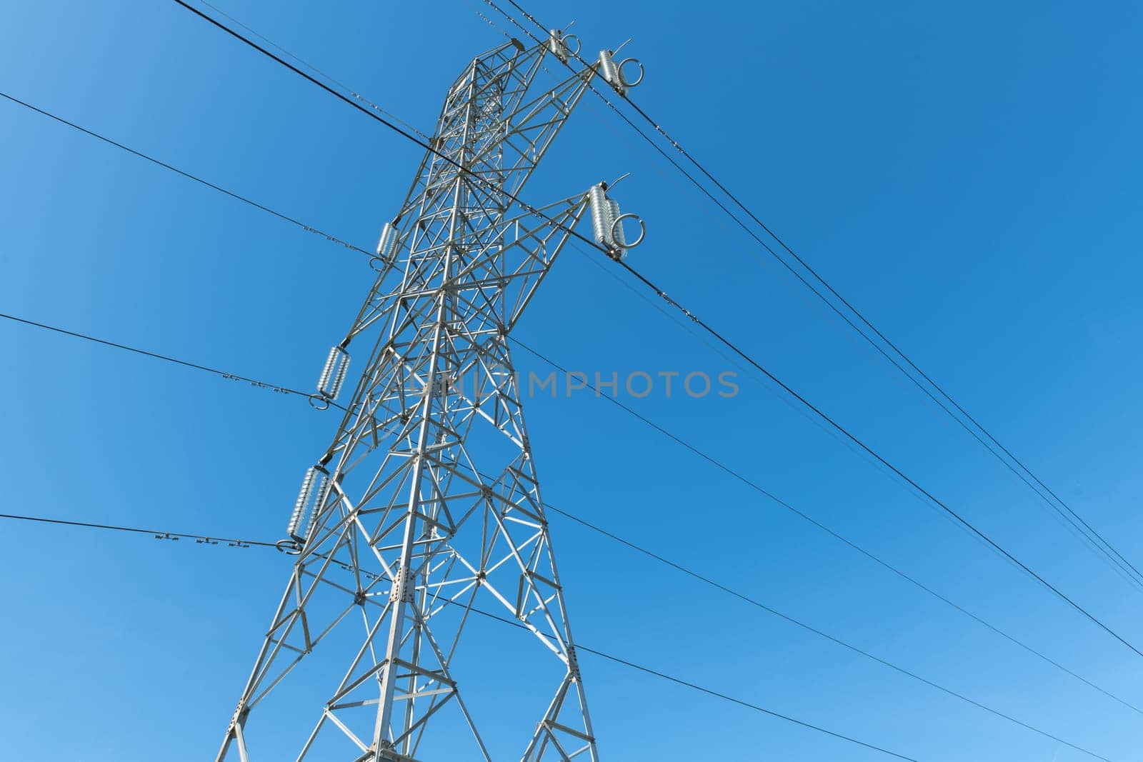 Electricity transmission pylon silhouetted against blue sky